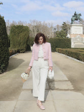 A lady wears a white shirt and a pink jacket.